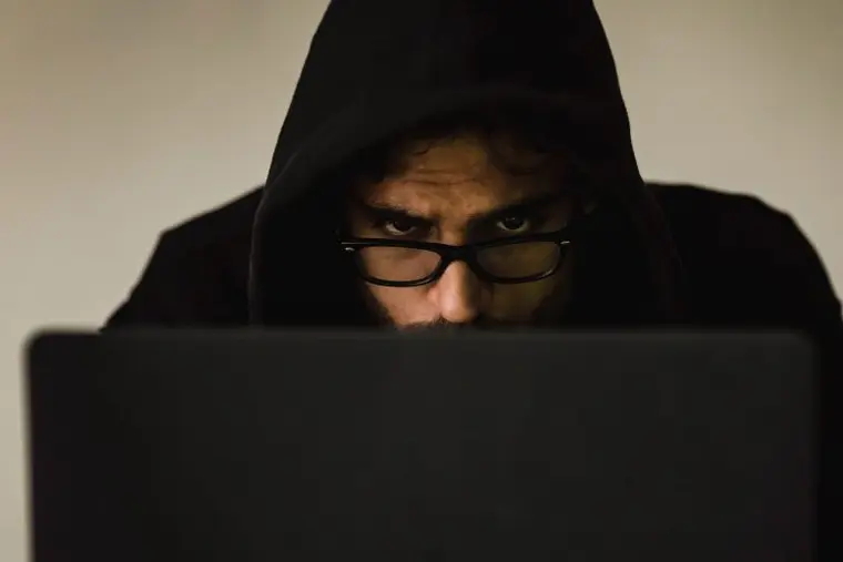 hacker man looking over laptop